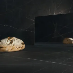 Caesarstone Impermia surface with a loaf of bread and reflective mirror, showcasing its sleek design.