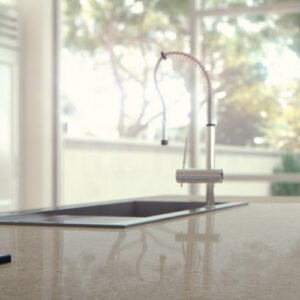 Modern kitchen with Caesarstone Shitake Quartz worktop, featuring a sleek sink and hob, overlooking a garden in a UK home.