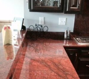Modern kitchen with Dragon Red Granite countertops and dark cabinetry in the UK.