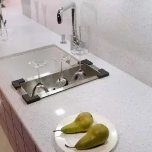 Modern kitchen with Technistone Crystal Diamond Quartz worktop, featuring a sink and pears on a plate.