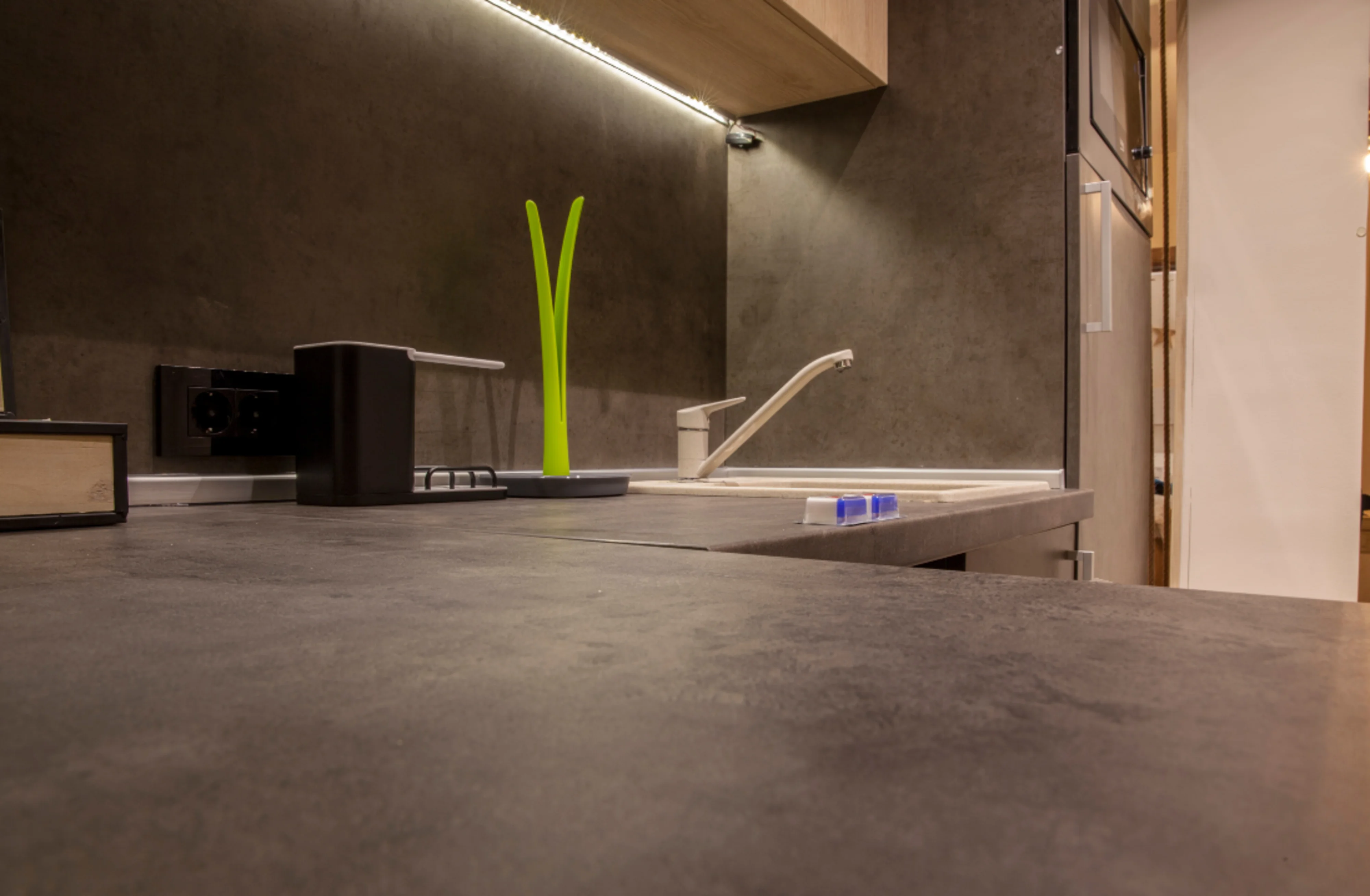 A black kitchen Neolith worktop with a grey sink.