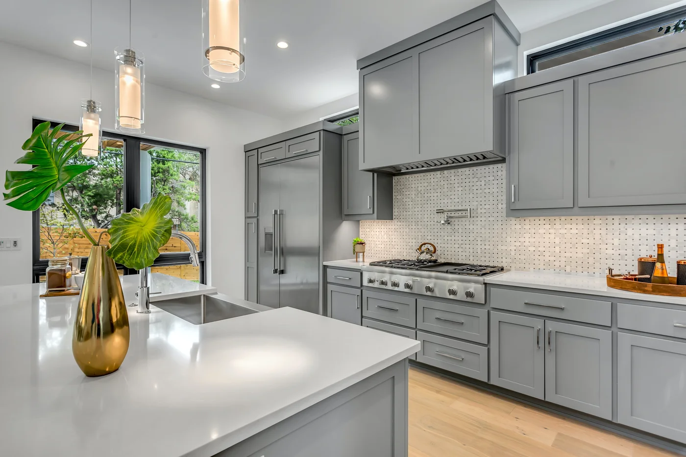 Grey kitchen ideas. A grey kitchen with an island and a plant.