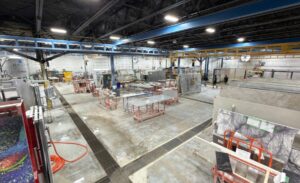 Interior of a stone processing facility with various machinery and stone slabs