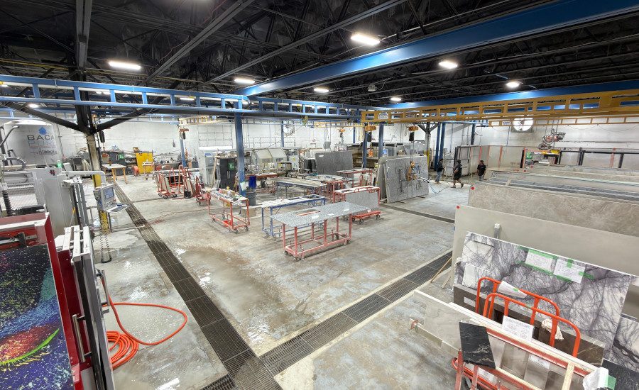 Interior of a stone processing facility with various machinery and stone slabs